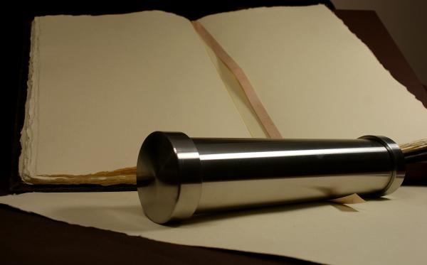 Księga pamiątkowa z papieru czerpanego, obłożona w skórę i stalowa tuba.